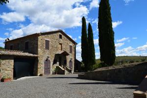 ein altes Steingebäude mit Bäumen davor in der Unterkunft Villa San Sebastiano Montalcino in Montalcino