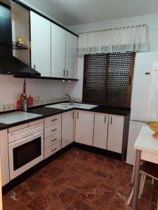 a kitchen with white cabinets and a sink and a refrigerator at Casa de la Gloria in Baños de la Encina