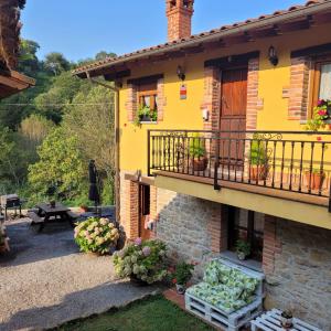 a yellow house with a balcony and a patio at Carroceu Rural in Cangas de Onís