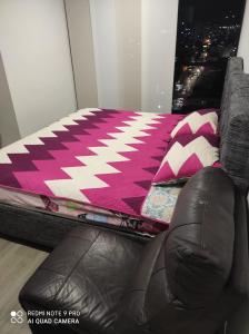 a bed with a pink and white rug next to a window at APARTAMENTO TORRES DE BARLOVENTO in Ibagué