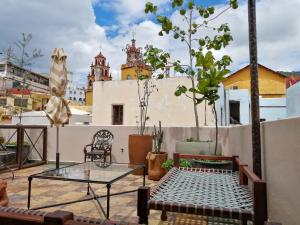 un patio con una mesa de cristal y sillas en el techo en Casona Alonso 10- Hotelito Mexicano en Guanajuato