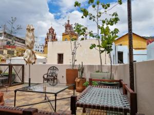 a patio with a glass table and chairs on a roof at Casona Alonso 10- Hotel Boutique in Guanajuato