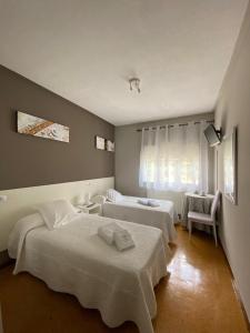 a hotel room with two beds and a window at Pensión NAVIA A Pontenova in A Pontenova