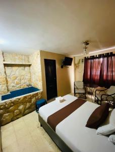 1 dormitorio con 1 cama grande y pared de piedra en Hostal Bellagio, en Guayaquil
