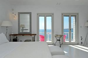 a white bedroom with a bed and a view of the ocean at Villa Kastro in Parikia