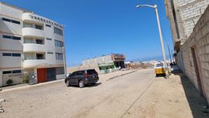 聖胡安的住宿－Ensenada Hotel，停在建筑物旁边的土路上的车辆