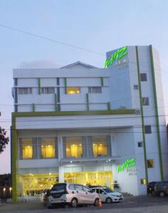 芝拉劄的住宿－Whiz Prime Hotel Sudirman Cilacap，两辆车停在大楼前的建筑物