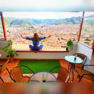a woman sitting on a window ledge looking out at a city at Casa Mirador in Cusco