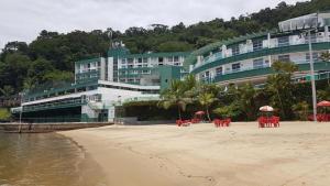un hotel en la playa con mesas y sombrillas en Flat a beira mar em Angra dos Reis, en Angra dos Reis