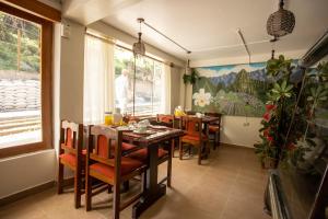 une salle à manger avec une table, des chaises et un homme dans l'établissement Hostal La Payacha, à Machu Picchu
