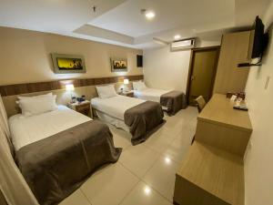 a hotel room with two beds and a television at Bella Vista Hotel - Encarnación in Encarnación