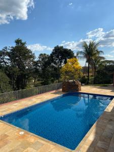 a swimming pool in a backyard with a fence and trees at Chácara Cantinho que Deus me Deu in Sao Paulo
