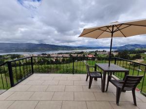 a table and chairs with an umbrella on a balcony at ReLuna Guatavita Glamping & Suites in Guatavita