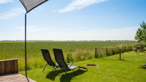 two chairs sitting on the lawn under an umbrella at Beleef het Noorden in Groningen