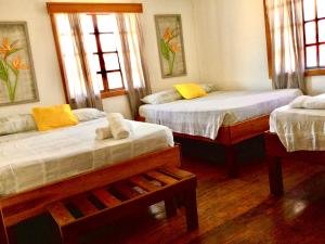a bedroom with two beds and two windows at Hostal del Mar - Main Street in Bocas del Toro