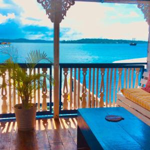 uma vista para o oceano a partir de uma varanda com um sofá em Hostal del Mar - Main Street em Bocas del Toro