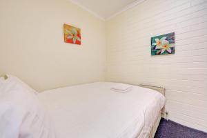 a bedroom with a white bed with two pictures on the wall at Snow Ski Apartments 34 in Falls Creek