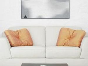 Belvilla by OYO Tipologia trio في البندقية: أريكة بيضاء مع وسادتين برتقاليتين عليها