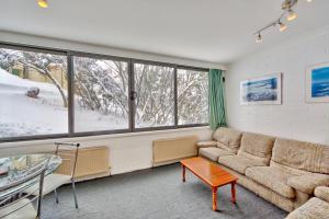 a living room with a couch and a table and windows at Snow Ski Apartments 05 in Falls Creek