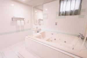 een witte badkamer met een bad en een toilet bij Guest Motel- Zhongli Branch in Pingzhen