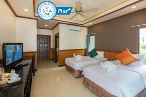 a hotel room with two beds and a flat screen tv at Sunrise Resort- Koh Phangan - SHA Extra Plus in Haad Rin