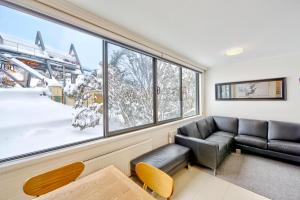 a living room with a couch and a large window at Snow Ski Apartments 07 in Falls Creek