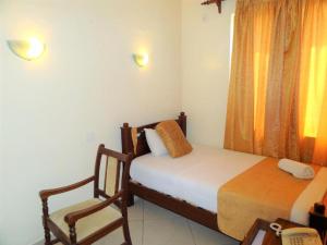 1 dormitorio con 2 camas, silla y ventana en Regency Park Hotel, en Mombasa