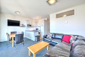 Una sala de estar con un sofá y una mesa y una cocina. en Snow Ski Apartments 28, en Falls Creek
