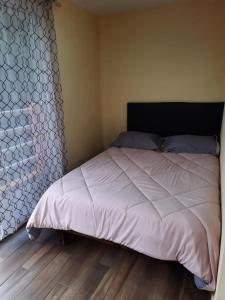 uma cama num pequeno quarto com piso em madeira em Posada Tres Marías Un rincón de Magia Zacateca. em Zacatlán