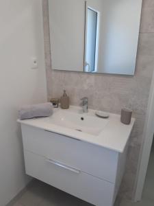 ein Badezimmer mit einem weißen Waschbecken und einem Spiegel in der Unterkunft Maison entre Mer et Brière. Proche de La Baule et de Guérande. in Saint-André-des-Eaux