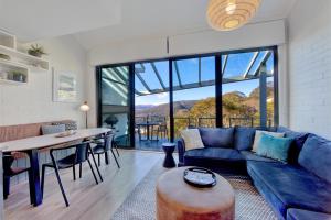a living room with a blue couch and a table at Snow Ski Apartments Penthouse 33 in Falls Creek