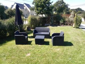 a group of chairs and an umbrella in the grass at Maison entre Mer et Brière. Proche de La Baule et de Guérande. in Saint-André-des-Eaux
