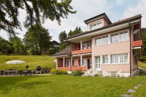 a pink house with a patio and a yard at Chalet Bergli in Rigi Kaltbad