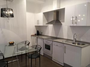 a kitchen with white cabinets and a table with chairs at Casa Cosy in Valencia