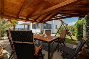 Una mesa y sillas de madera en un patio. en MALO Ferienvilla Privlaka, Pool, Boje, WI-FI, Wallbox, en Privlaka