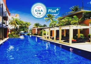 
a large swimming pool in a city with palm trees at La Flora Resort Patong - SHA Extra Plus in Patong Beach
