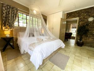 a bedroom with a bed with a mosquito net at Masasana’s Rest in Hazyview