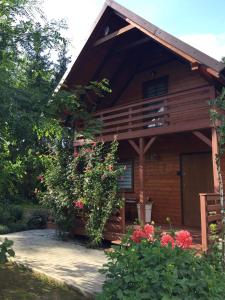 una cabaña de madera con flores delante en Domek Nad Brzegiem en Witanowice