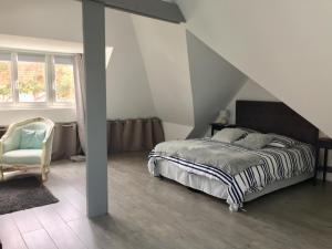 a bedroom with a bed and a chair at Villa La Croisée des Chemins in Bray-Dunes
