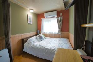 a small bedroom with a bed and a window at C HOTEL 美瑛白金 - Biei Shirogane in Biei