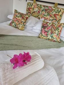 a white bed with a pink flower on it at Impunzi Place in Kloof