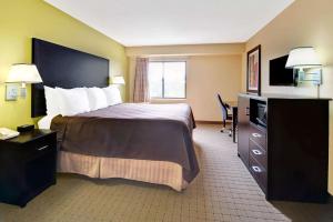 a hotel room with a large bed and a television at Days Inn & Suites by Wyndham DeSoto in DeSoto