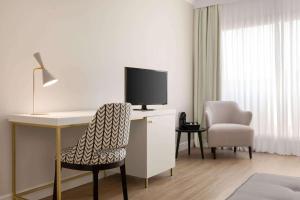 a hotel room with a desk with a tv and a chair at Hotel Avenue Louise Brussels Trademark Collection by Wyndham in Brussels