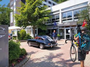 a man standing next to a car in front of a building at HARZ HOTEL und Gästehaus am Bornweg in Bad Sachsa