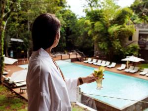 a woman holding a drink in front of a pool at Mercure Iguazu Hotel Iru in Puerto Iguazú