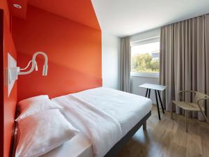 バイロイトにあるibis budget Bayreuthのオレンジ色の壁のベッドが備わるホテルルームです。