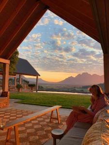 a woman sitting on a porch with a laptop at 7 Koppies in Franschhoek