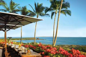 - une table avec des fleurs, des palmiers et l'océan dans l'établissement Four Seasons Resort Lana'i, à Lanai City