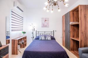 a bedroom with a purple bed and a chandelier at CLOSE TO AIRPORT - private room with private bathroom ADULTS ONLY in Gudja