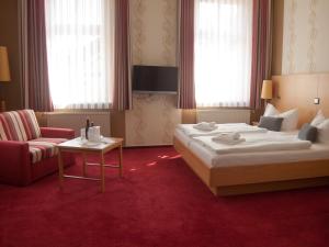 une chambre d'hôtel avec un lit et une chaise dans l'établissement Hotel & Restaurant Waldschlösschen, à Kyritz